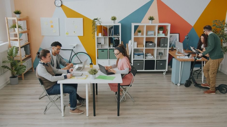 Diverse professionals collaborating in an office, utilizing AI copywriting tools for creative work.
