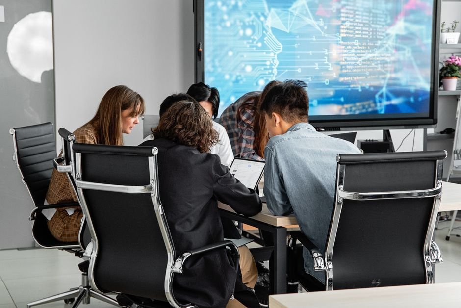 Modern workspace with diverse professionals collaborating and integrating AI technology into their creative processes.